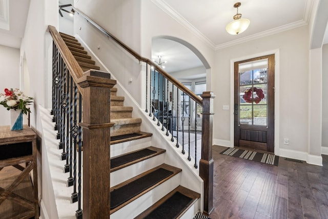 entrance foyer with arched walkways, baseboards, wood finished floors, and crown molding