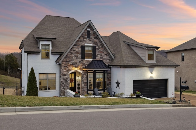 view of front of home featuring brick siding, an attached garage, fence, and stone siding