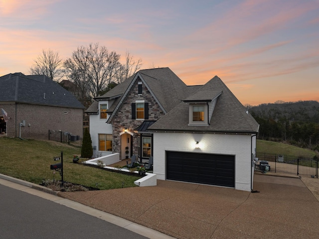 view of front of property featuring a front yard, stone siding, fence, a shingled roof, and driveway