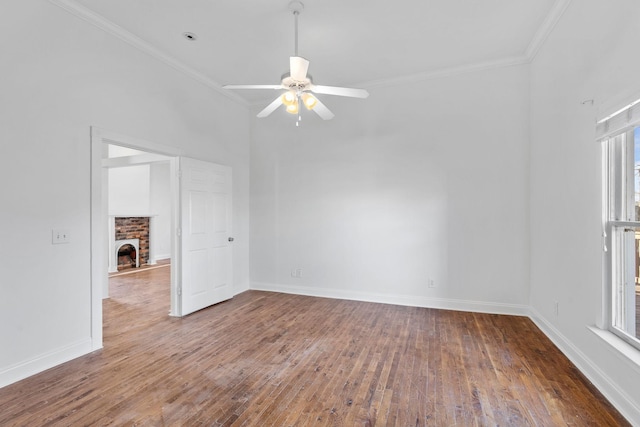 unfurnished room featuring a brick fireplace, baseboards, crown molding, and wood finished floors