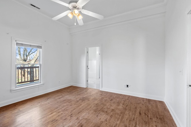 empty room featuring crown molding, baseboards, ceiling fan, and wood finished floors