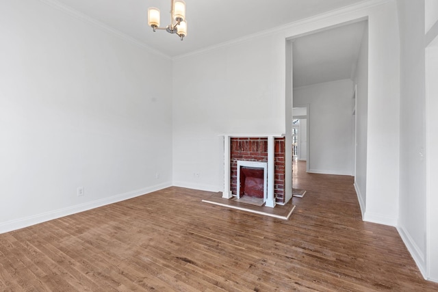 unfurnished living room featuring a fireplace, wood finished floors, baseboards, an inviting chandelier, and crown molding