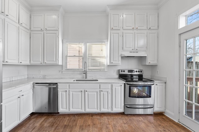 kitchen with white cabinets, appliances with stainless steel finishes, ornamental molding, under cabinet range hood, and a sink