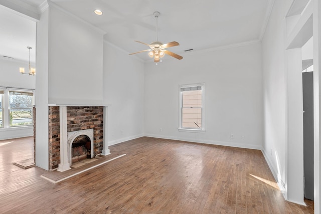 unfurnished living room featuring baseboards, ornamental molding, wood finished floors, a fireplace, and ceiling fan with notable chandelier