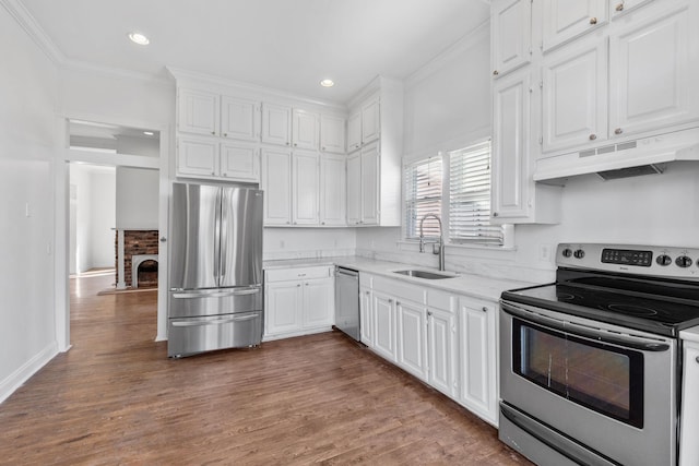 kitchen featuring under cabinet range hood, stainless steel appliances, a sink, white cabinetry, and ornamental molding