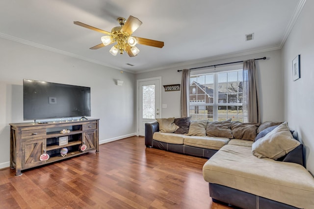 living room featuring wood finished floors, a ceiling fan, visible vents, baseboards, and ornamental molding