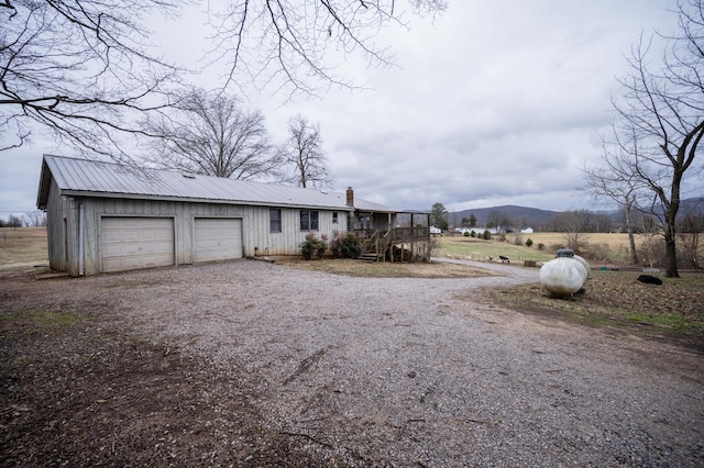 view of front of home with metal roof, driveway, a chimney, and an attached garage