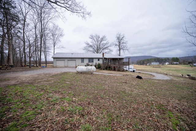 view of front of home featuring a garage, metal roof, dirt driveway, and a mountain view