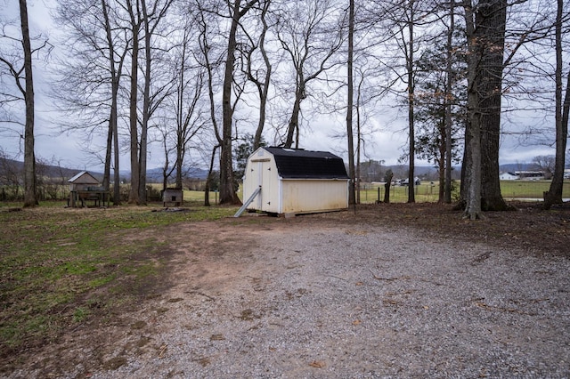 view of yard with an outdoor structure, driveway, and a storage shed