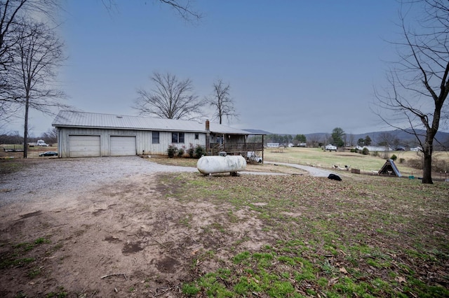 view of front of property with metal roof, an attached garage, and dirt driveway