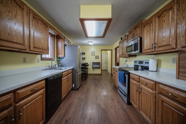 kitchen with light countertops, appliances with stainless steel finishes, a sink, and brown cabinets