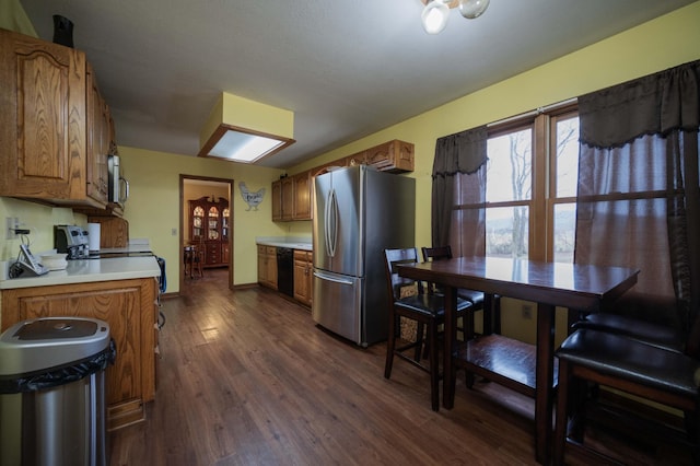 kitchen with baseboards, brown cabinetry, appliances with stainless steel finishes, dark wood-type flooring, and light countertops