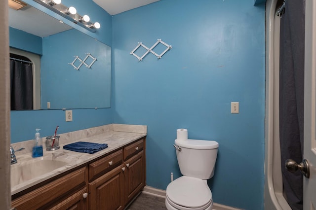 bathroom featuring toilet, baseboards, wood finished floors, and vanity