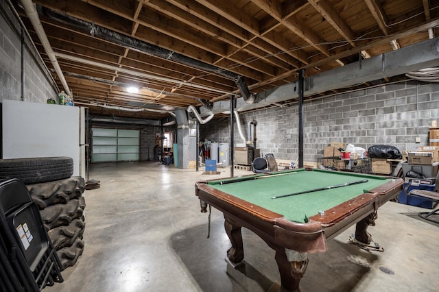 game room featuring concrete flooring, concrete block wall, a garage, and heating unit