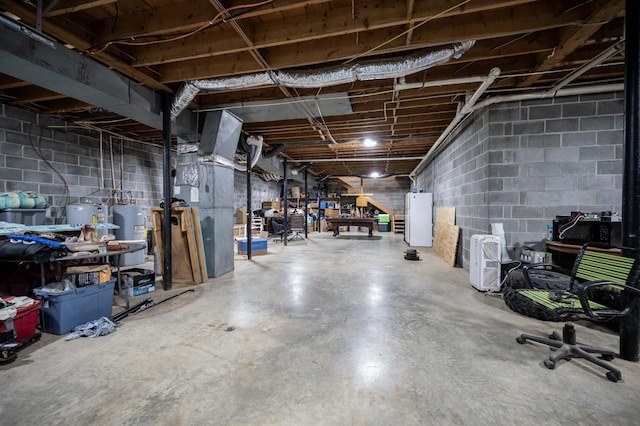 unfinished below grade area with water heater, freestanding refrigerator, and concrete block wall