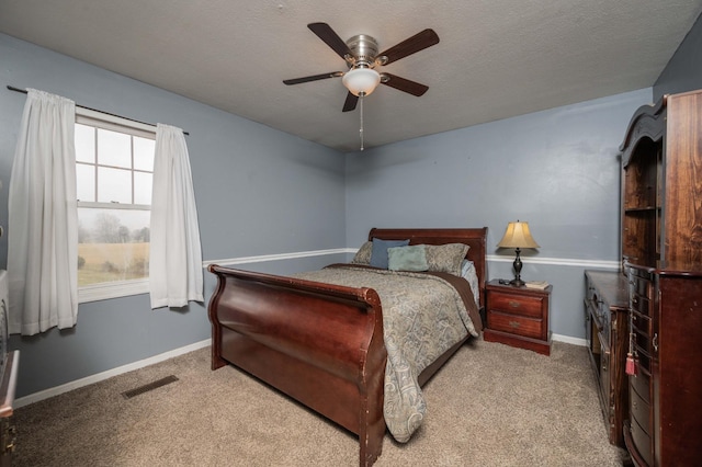 carpeted bedroom with a textured ceiling, a ceiling fan, visible vents, and baseboards