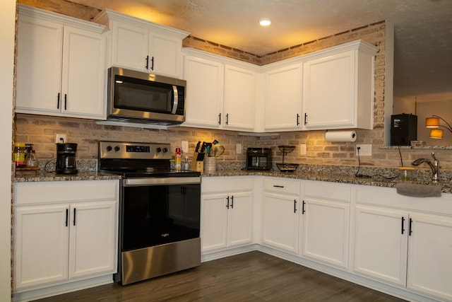 kitchen with dark stone counters, stainless steel appliances, and white cabinetry