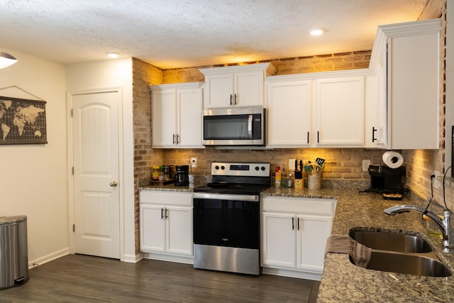 kitchen with white cabinets, appliances with stainless steel finishes, dark wood-type flooring, a sink, and backsplash