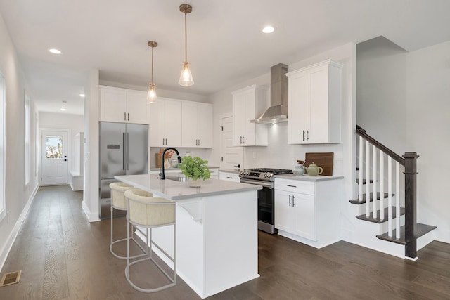 kitchen with decorative backsplash, dark wood-style floors, wall chimney exhaust hood, appliances with stainless steel finishes, and a sink