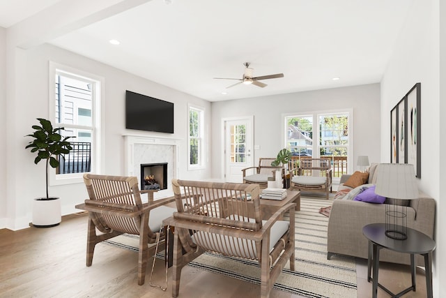 living area with a wealth of natural light, light wood-style flooring, recessed lighting, and a premium fireplace