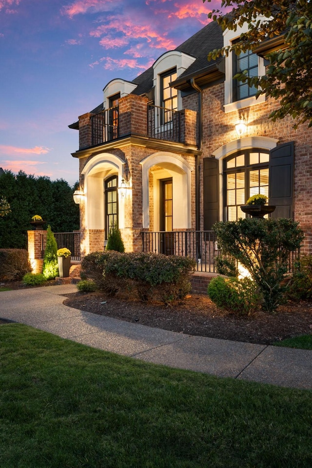 view of front of home with brick siding and a balcony