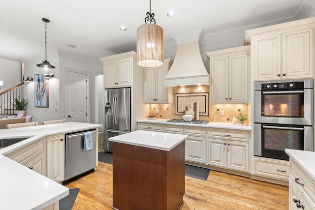 kitchen with ornamental molding, stainless steel appliances, premium range hood, and light wood-style floors