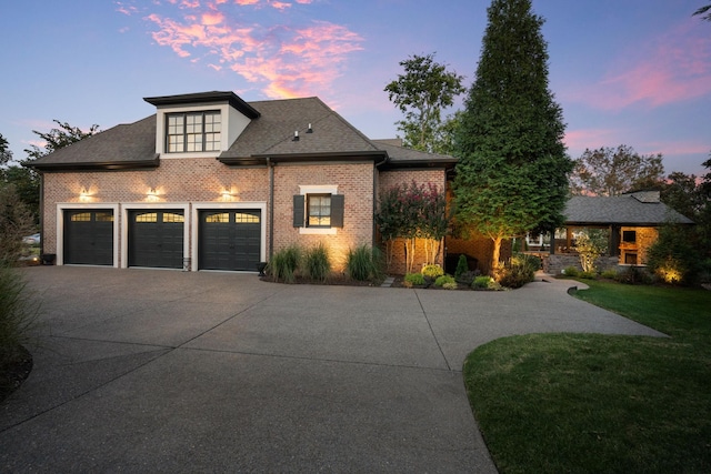 view of front of home with a garage, driveway, brick siding, and a front lawn