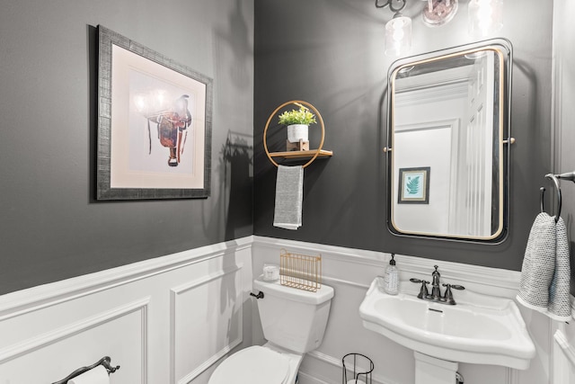 bathroom with a wainscoted wall, a sink, and toilet