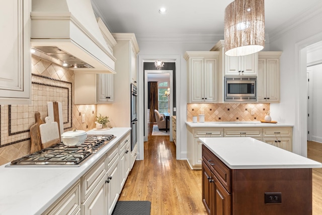 kitchen with stainless steel appliances, premium range hood, light countertops, ornamental molding, and light wood-type flooring