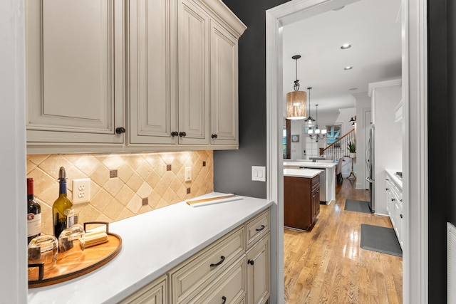 kitchen featuring freestanding refrigerator, light countertops, cream cabinetry, light wood-style floors, and backsplash