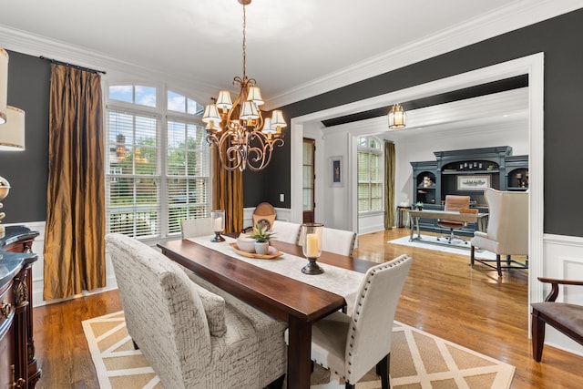 dining space with crown molding, a chandelier, wood finished floors, and a healthy amount of sunlight