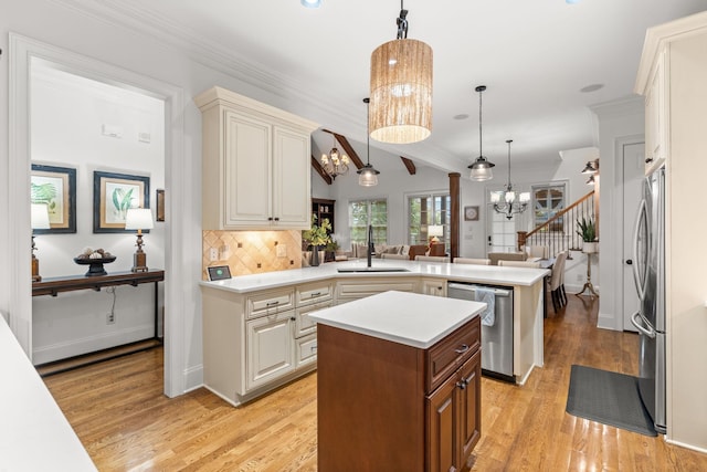 kitchen featuring a center island, a peninsula, an inviting chandelier, stainless steel appliances, and light countertops