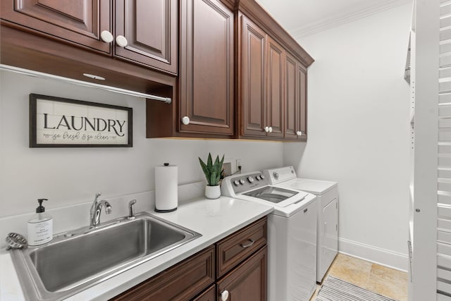 laundry room featuring cabinet space, ornamental molding, washing machine and dryer, a sink, and baseboards