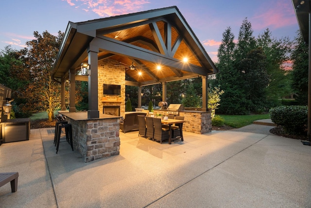 view of patio / terrace featuring an outdoor stone fireplace, area for grilling, outdoor dry bar, a gazebo, and grilling area