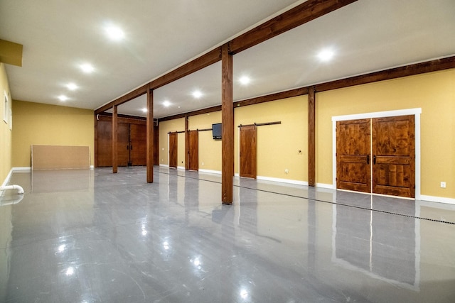 below grade area featuring a barn door and baseboards