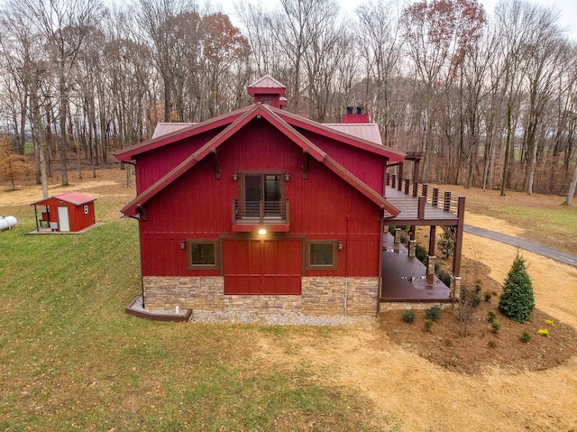 view of home's exterior featuring a lawn, a patio area, metal roof, stone siding, and an outdoor structure