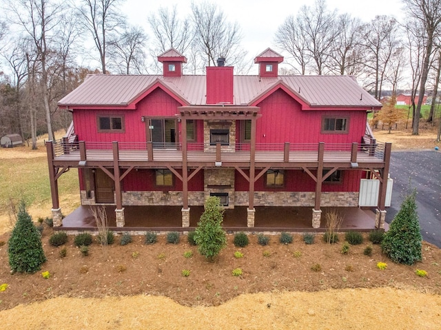 back of house featuring metal roof, stone siding, and a wooden deck