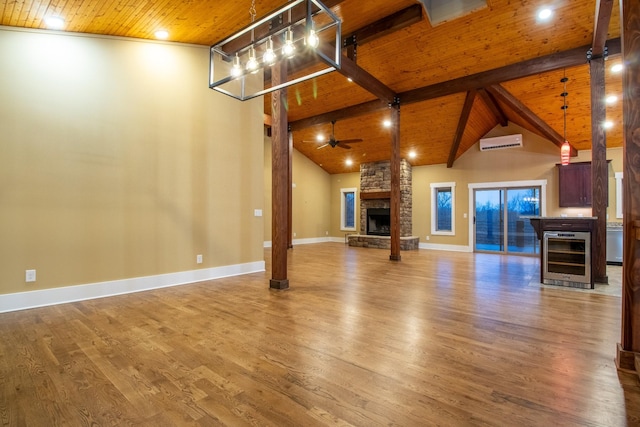 unfurnished living room featuring wooden ceiling, a wall unit AC, a stone fireplace, and wood finished floors