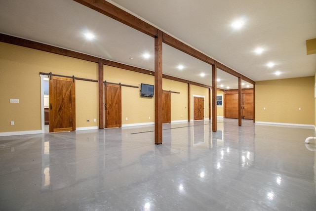 basement featuring a barn door, recessed lighting, and baseboards