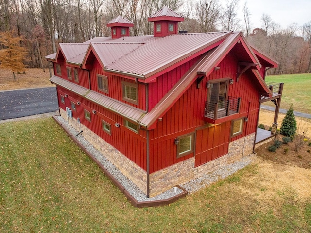 view of home's exterior with metal roof, aphalt driveway, board and batten siding, and a yard