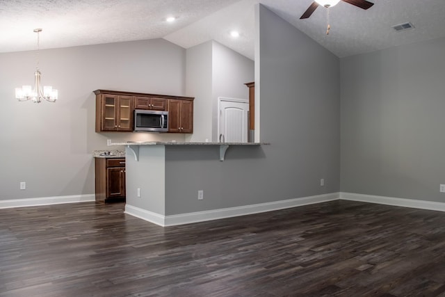 kitchen with a breakfast bar, dark wood-style flooring, stainless steel microwave, and visible vents