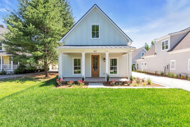 modern farmhouse with metal roof, a standing seam roof, covered porch, a front lawn, and board and batten siding