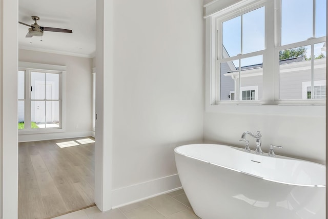 bathroom with baseboards, crown molding, a freestanding bath, and ceiling fan