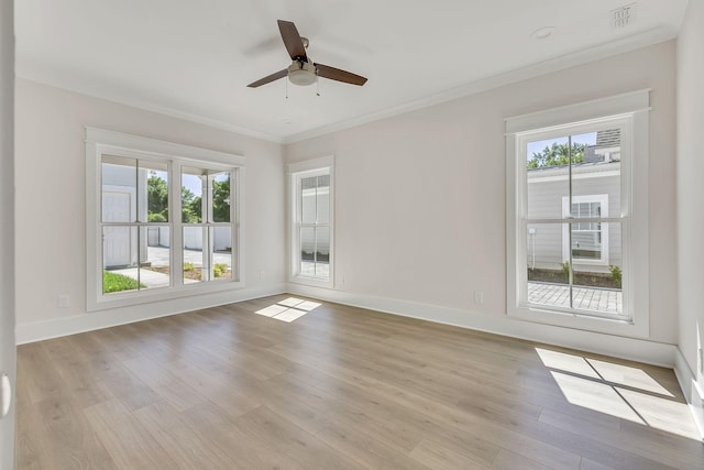 spare room featuring ornamental molding, light wood finished floors, plenty of natural light, and visible vents