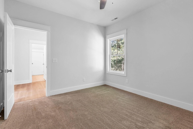 carpeted empty room with visible vents, ceiling fan, and baseboards