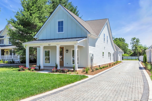 modern farmhouse style home featuring roof with shingles, covered porch, a standing seam roof, a front lawn, and board and batten siding