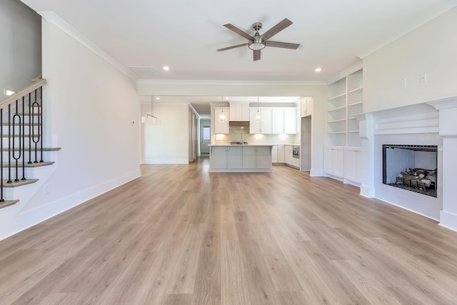 unfurnished living room featuring baseboards, light wood finished floors, a ceiling fan, and crown molding