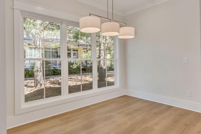 unfurnished dining area featuring ornamental molding, light wood-type flooring, and baseboards