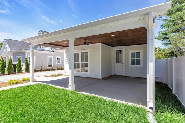 rear view of property featuring fence, a ceiling fan, a yard, a carport, and a patio area