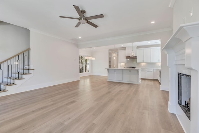 unfurnished living room featuring ornamental molding, a fireplace, and light wood-style floors